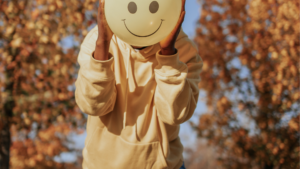 Une personne qui tient un ballon avec un smiley sourire avec fond d'arbres