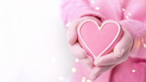 Cœur en gâteau rose tenu par une personne habillée en rose