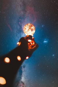 une main qui tient une lampe dans la nuit et qui brille